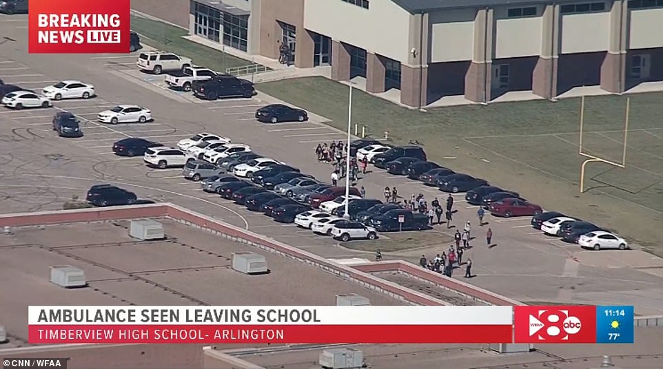 Large groups of people are seen above in the parking lot of Timberview High School in Arlington on Wednesday