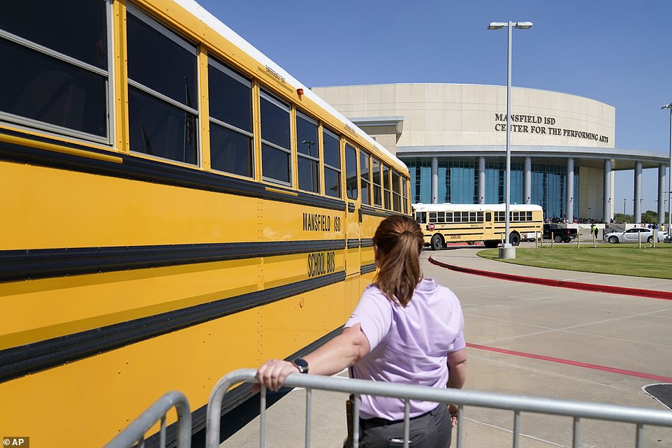School busses depart past a law enforcement official after dropping off Timberview High School children at the Mansfield ISD Center For The Performing Arts