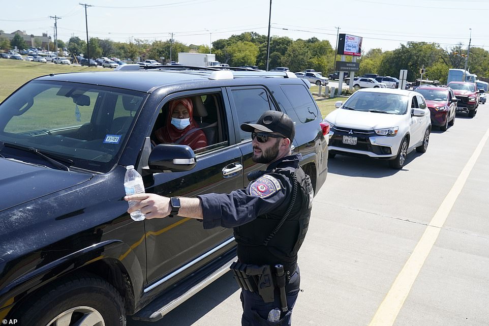 A Burleson, Texas, SWAT officer directs traffic to a parking area for families arriving to be reunited with their school children