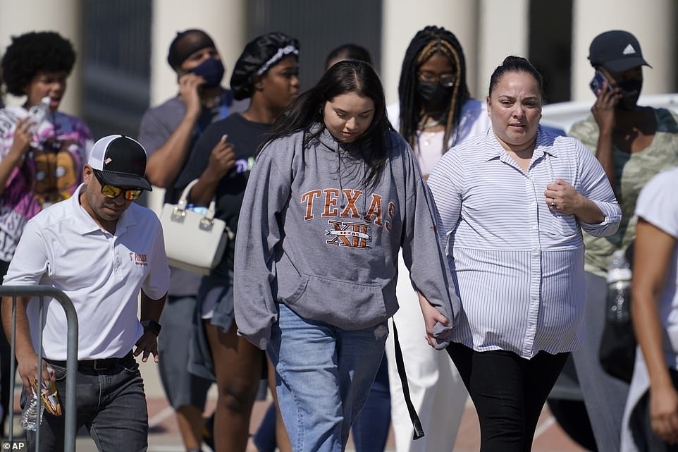 A woman and a teenage holds hands as they depart the Mansfield ISD Center For The Performing Arts Center where families were reunited with Timberview High School students on Wednesday