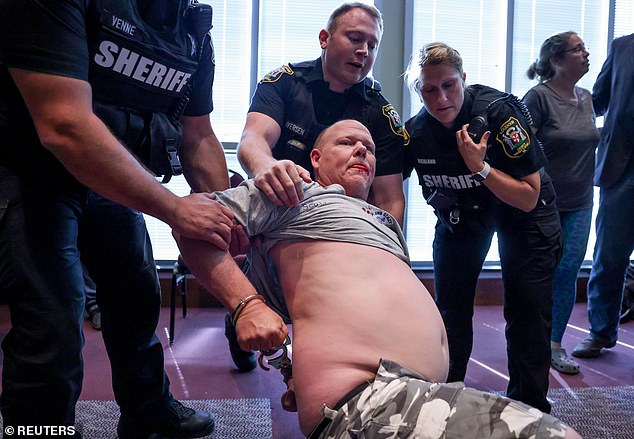 Scott Smith, the victim's father, was pictured with a bloody mouth, being dragged out of a school board meeting on June 22 - a month after the attack - after listening to school officials say no one had been sexually assaulted in the bathrooms when that's what his daughter had reported the previous month