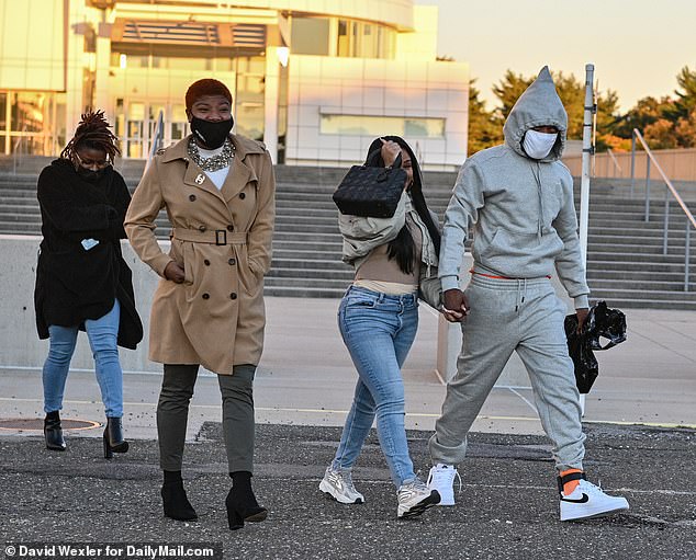 The rapper's sister Divinity Maxwell, in the brown trench coat, and his girlfriend, appeared to be smiling beneath their face masks as he was freed